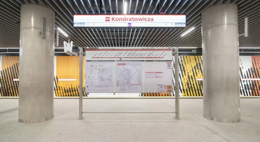 Tablica informacyjna na stacji **metro M2** Kondratowicza. Widoczne schematy stacji, sieci metra i informacje.