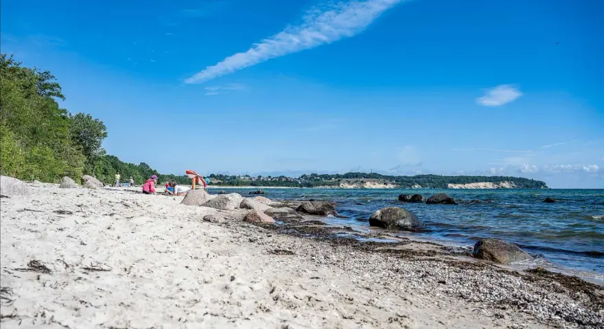 Kinder spielen am lobbe strand. Sand, Steine und das Meer bilden eine idyllische Szene unter blauem Himmel.
