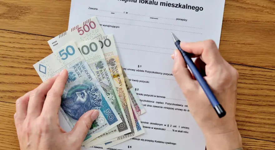 Umowa najmu i pieniądze na stole. Zastanawiasz się, jak zapłacić podatek od wynajmu mieszkania? Dokument i gotówka sugerują, że to czas na rozliczenie.
