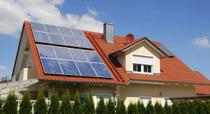 Dom z czerwoną dachówką i panelami fotowoltaicznymi. Mikroinstalacja PV na dachu zapewnia czystą energię.