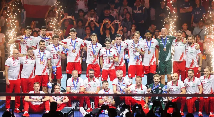 Polscy siatkarze świętują sukces na mistrzostwach świata w siatkówce 2026, z medalami na szyjach i flagą narodową w tle.