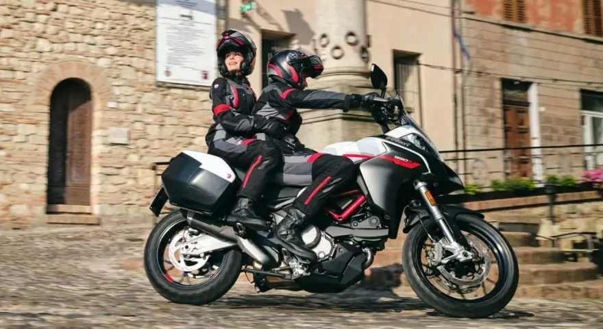 Para jadąca na sportowym motocyklu Ducati przez urokliwe, brukowane uliczki.