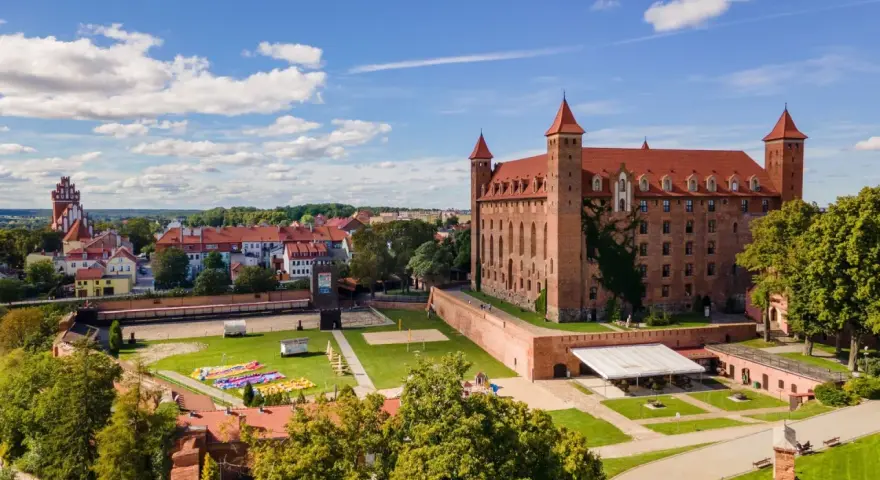 Zamek w Gniewie zaprasza na zwiedzanie. Potężna ceglana budowla z czerwonym dachem i wieżyczkami góruje nad miastem.