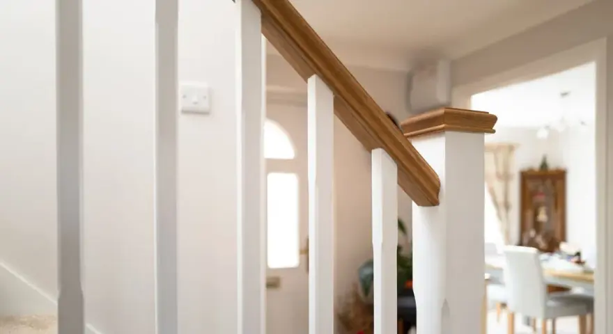 Barandilla de escalera blanca con pasamanos de madera, ideal para saber como modernizar una barandilla de madera.