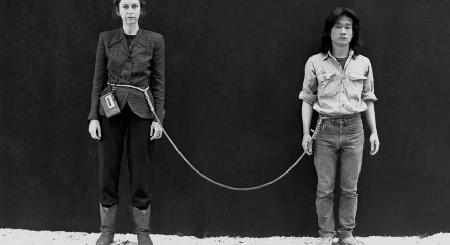 Une femme et un homme, reliés par une corde, dans une performance artistique saisissante.