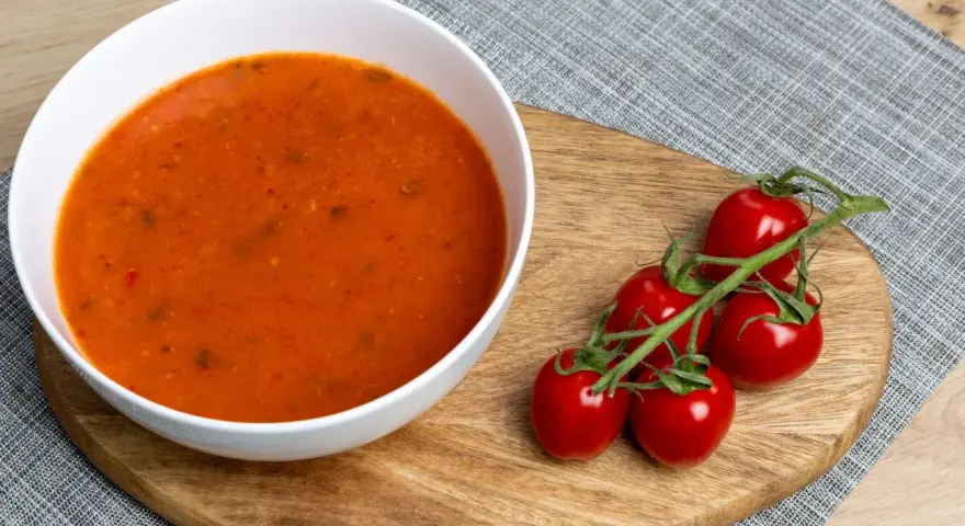Aksamitna zupa pomidorowa z ryżem czy z makaronem? Na desce leżą świeże pomidorki koktajlowe, idealne do tej klasycznej potrawy.