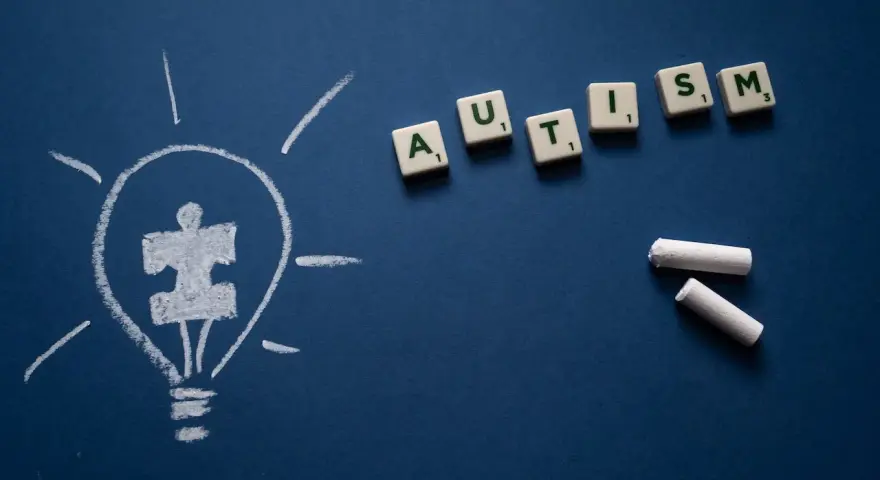 Żarówka z symbolem puzzli i litery tworzące słowo AUTISM. Wiele sławnych osób z autyzmem inspiruje nas każdego dnia.