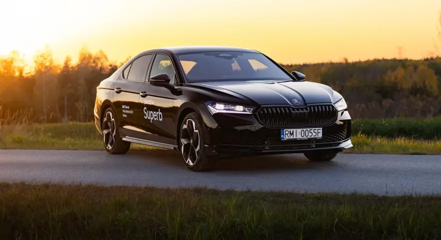 Czarny Skoda Superb 4 na tle zachodzącego słońca. Elegancki sedan z nowoczesnymi światłami i felgami.