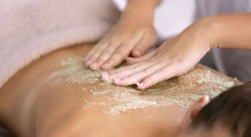 Manos expertas realizan un peeling corporal exfoliante, dejando la piel suave y renovada.