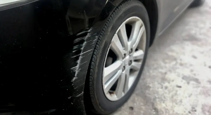 Scratches mar the black paint on a car's fender. Learn how to get scratches out of black car paint to restore its shine.