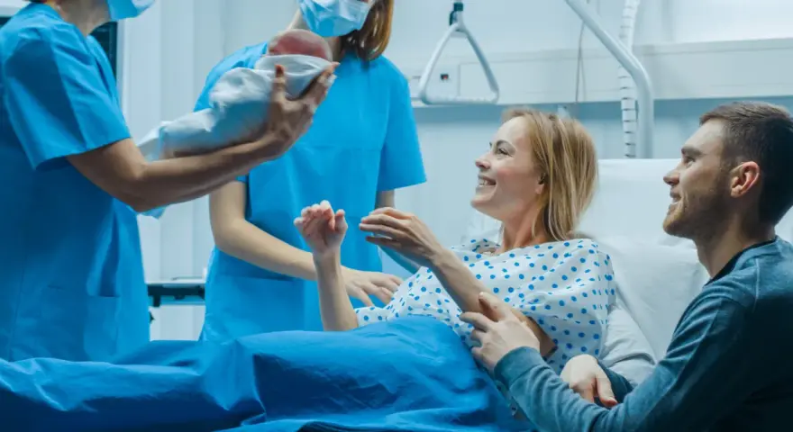 Szczęśliwi rodzice odbierają noworodka od położnej. Nauka i praktyka w najlepszym wydaniu, tworzą rodzinę.