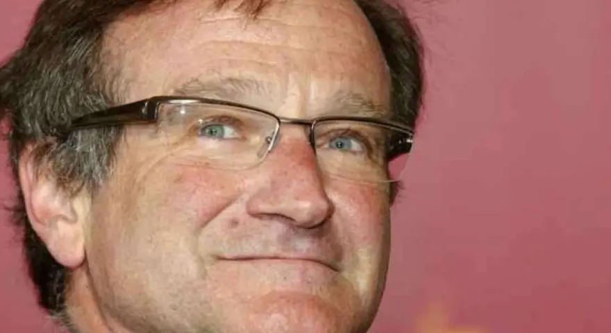 Primo piano di Robin Williams con occhiali, un uomo che ha portato gioia a molti, anche se il suo figlio morto non ha potuto vederlo.