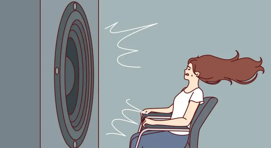Une femme assise, les cheveux au vent, face à un haut-parleur. Le son est si fort qu'il en devient une force physique, illustrant la définition du décibel.