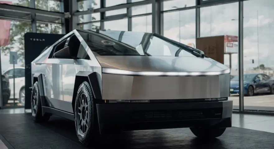 Tesla Cybertruck w salonie Tesli, z widokiem na ulicę przez okno.