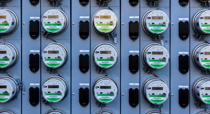Rząd liczników energii elektrycznej, zgodnych z dyrektywą MID, z cyfrowymi wyświetlaczami i zielonymi etykietami.