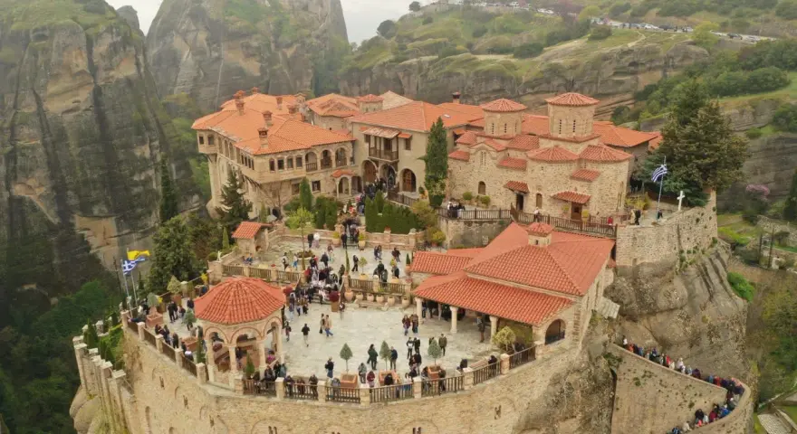 A stunning view of the monasteries of Meteora, perched atop towering rock formations. Visitors explore the courtyards and pathways, a testament to the enduring spirit of this sacred place.