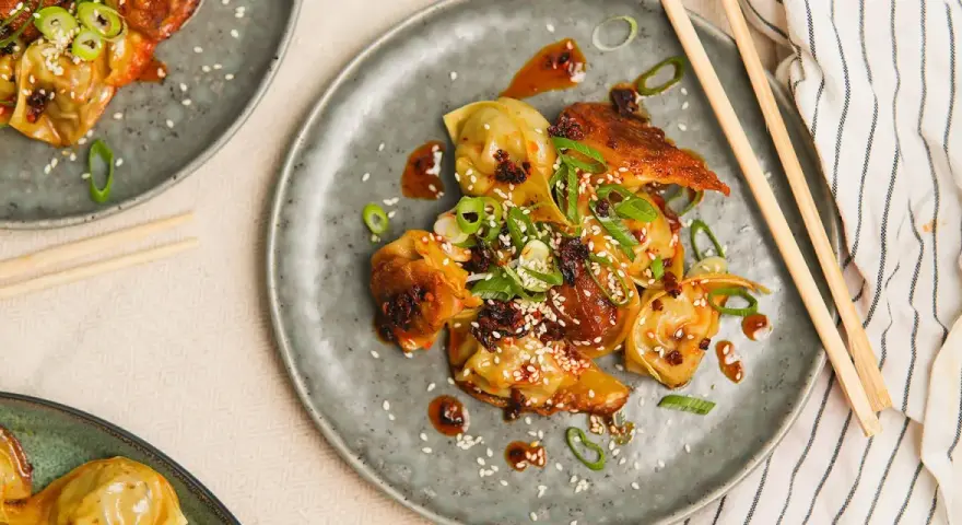 Stekta dumplings med en kryddig sås, toppade med sesamfrön och salladslök. En utsökt dumplings sås som gör rätten komplett.