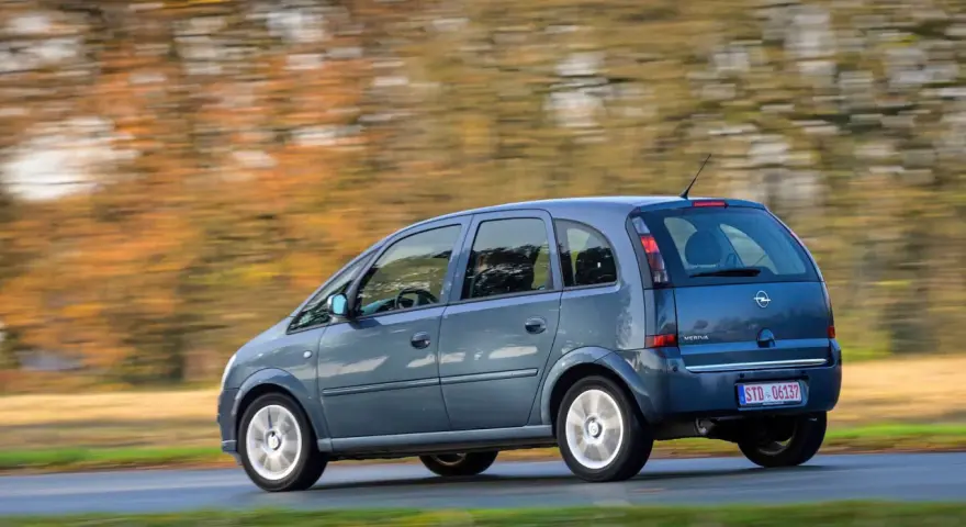 Blauer Opel Meriva A fährt durch eine herbstliche Landschaft. Bekannte Opel Meriva A Schwachstellen sind hier nicht sichtbar.