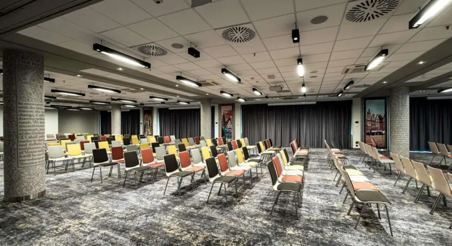 Sala konferencyjna w hotelu Mercure Wrocław, przygotowana na wydarzenie. Rzędy kolorowych krzeseł czekają na gości.
