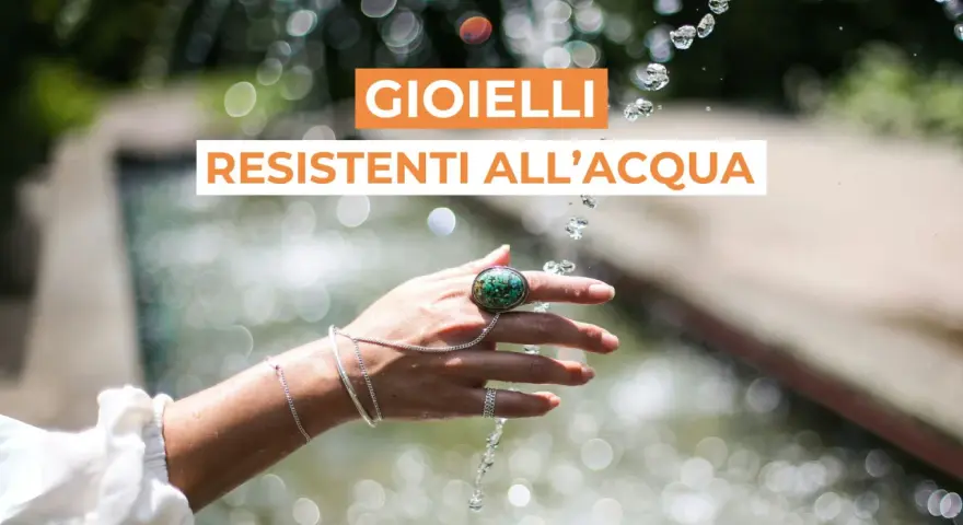 Mano adornata con gioielli che non si rovinano con l'acqua, sotto un getto d'acqua scintillante.