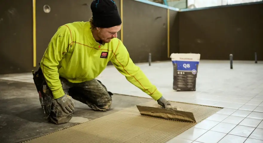 Man i gul jacka lägger fix på golvet för att byta ut det.