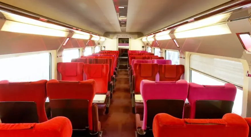 Rows of red and pink seats inside a train car, ready for passengers on the best train from Amsterdam to Paris.