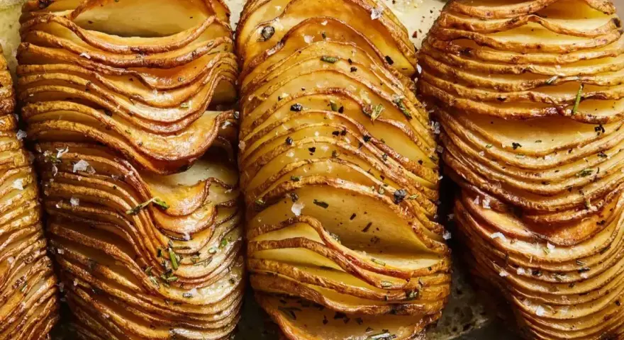 Krispiga hasselbackspotatisar, perfekt för ett enkelt hasselbackspotatis recept. Garnerade med örter och flingsalt.