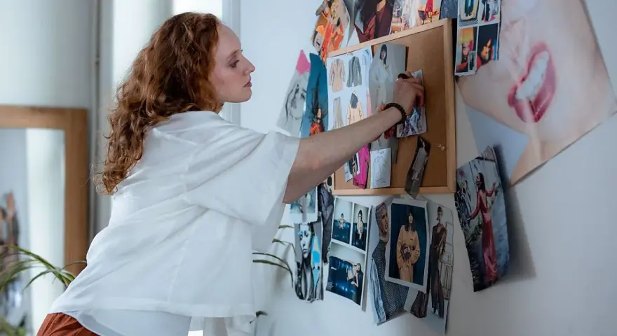 Frau mit roten Haaren arrangiert Modebilder für ihr Modemanagement Studium.