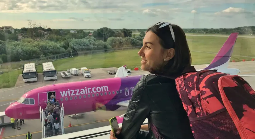Kobieta z plecakiem czeka na lot Wizzair. W samolocie można zabrać podręczny bagaż, np. plecak i telefon.