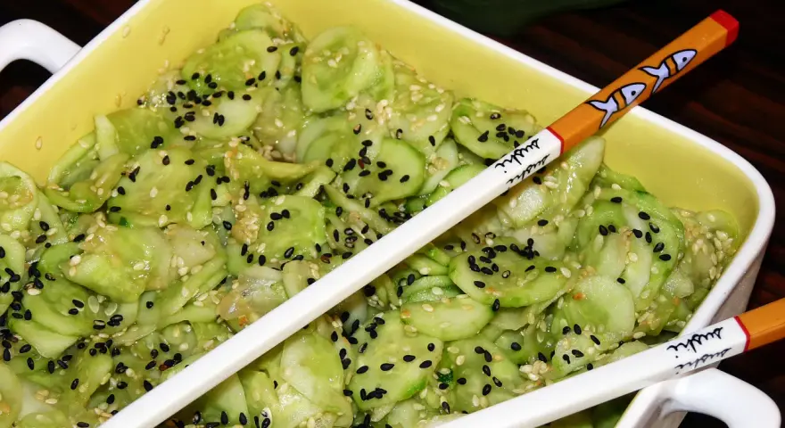 Pyszne ogórki po japońsku, posypane czarnym i białym sezamem, gotowe do jedzenia pałeczkami z motywem sushi.