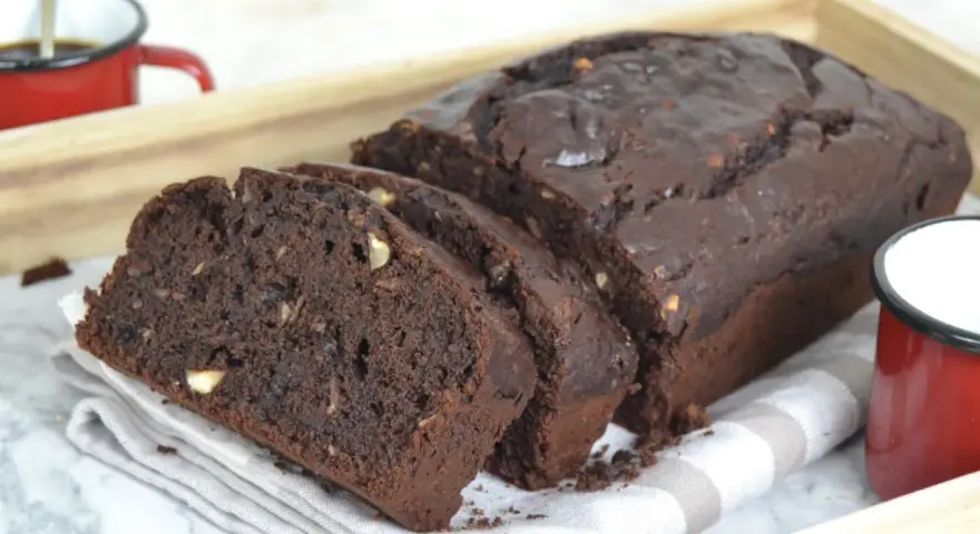 Bizcocho de platano y chocolate, recién horneado y cortado en rebanadas, con trozos de nuez visibles.