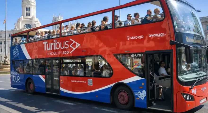 Tourists enjoy a hop on hop off bus tour of Madrid, Spain, with the iconic Turibus double-decker bus.