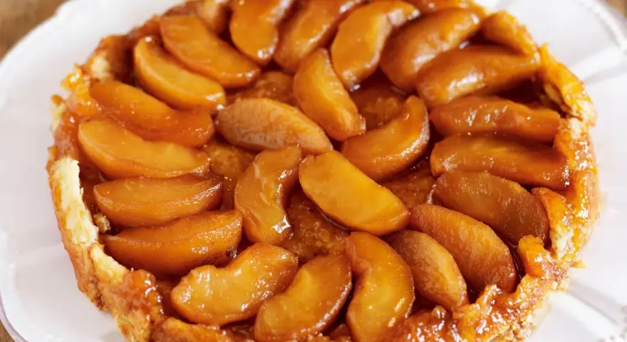 En gyllene tarte tatin med karamelliserade äppelklyftor som glänser. En klassisk fransk dessert som smälter i munnen.