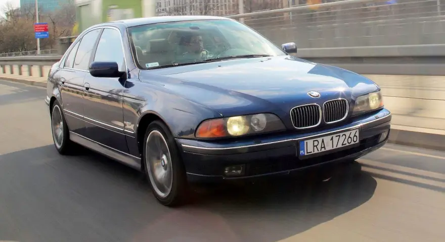 Niebieskie BMW serii 5 (E39) z silnikiem m52b20 jedzie po moście.