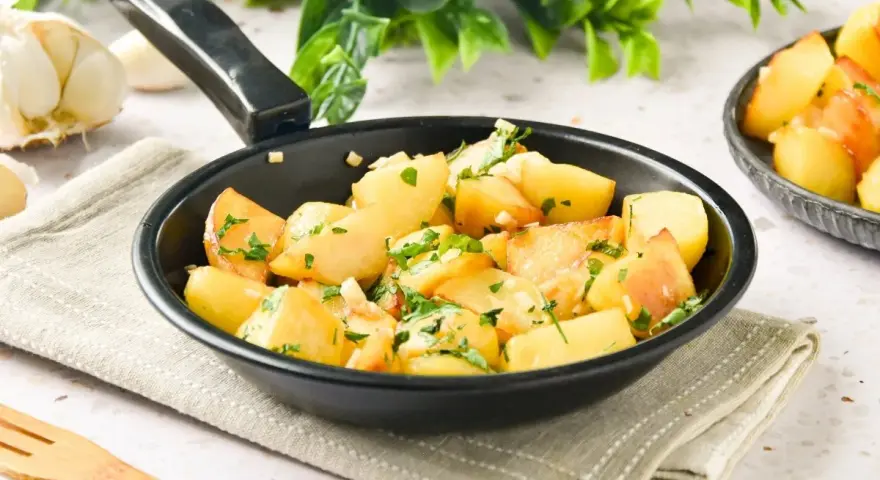 Patatas al ajillo recién hechas en sartén, con perejil fresco y ajos picados. ¡Un plato sencillo y delicioso!