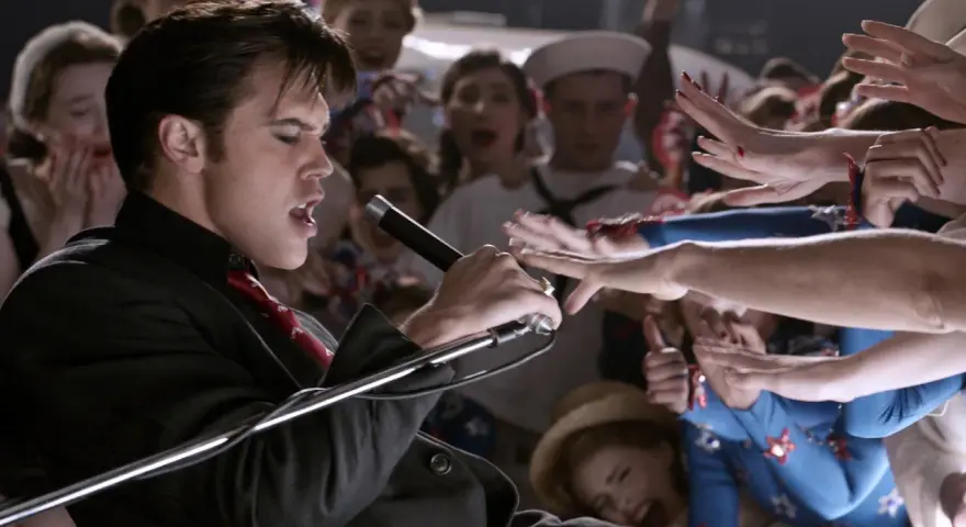 Elvis Presley, der Film: Ein junger Elvis singt mit Leidenschaft ins Mikrofon, umringt von jubelnden Fans.