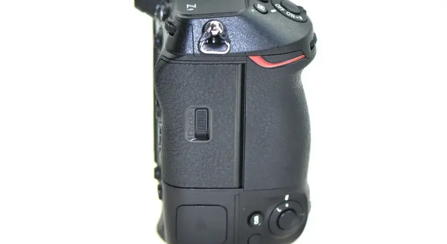 Boczny widok aparatu Nikon Z9, gotowego do testów. Widoczny slot na kartę pamięci i przyciski sterujące.