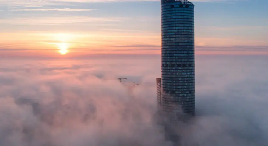 Sky Tower Wrocław, jego imponująca wysokość ginie we mgle o wschodzie słońca. Widok zapiera dech.