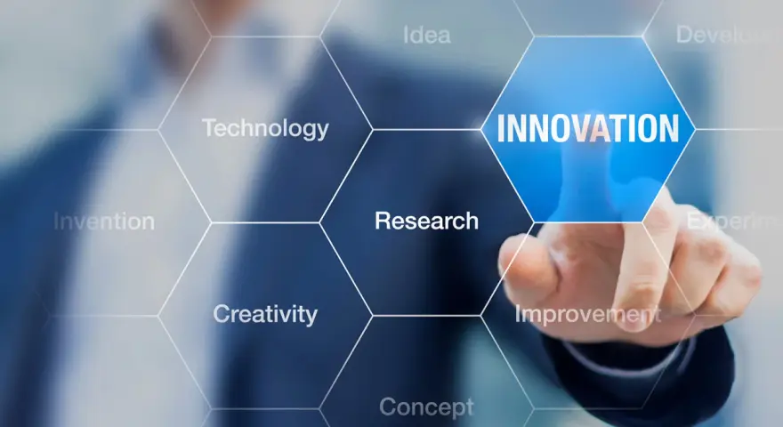 Dłoń dotyka ekranu z napisem "INNOVATION", otoczonego przez sześciokąty z hasłami: Idea, Technology, Research, Creativity, Invention, Improvement. To wizualizacja procesu, który może być częścią wzornictwo przemysłowe studia.