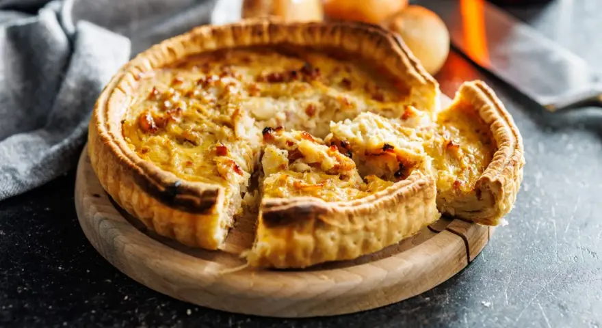 Une quiche lorraine dorée, prête à être dégustée. La cuisson est parfaite, la pâte croustillante et la garniture onctueuse.