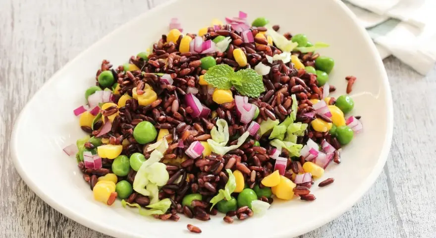 Insalata colorata con riso venere, piselli, mais, cipolla rossa e lattuga. Un'idea fresca per le tue riso venere ricette.