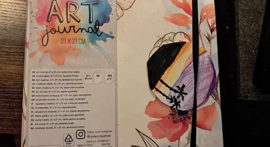Pierwsza strona szkicownika z napisem "ART journal" i kolorowymi kwiatami. Na okładce widoczny fragment rysunku.