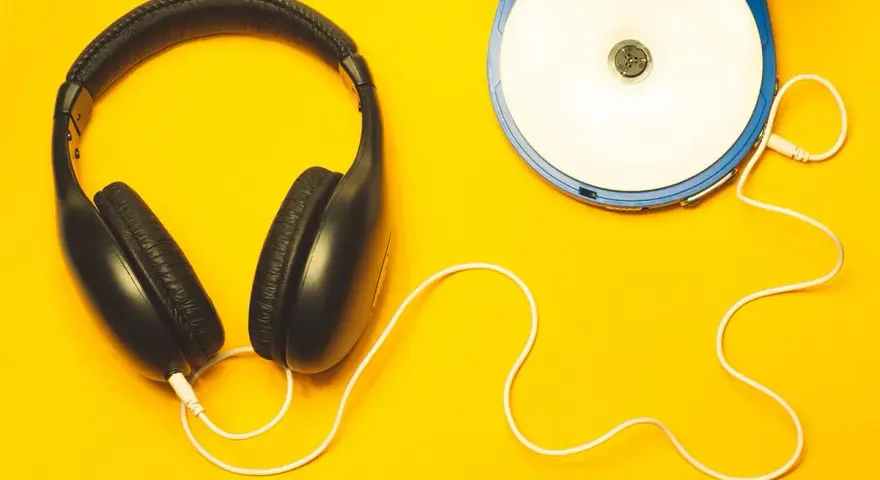 Kopfhörer und ein Discman auf gelbem Hintergrund. Perfekt, um neue Musik zu promoten und den Sound zu genießen.