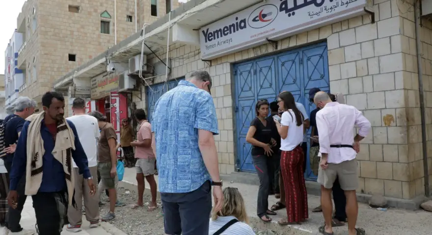 Ludzie stoją przed biurem Yemenia Airways. Czy Jemen jest bezpieczny? To pytanie zadają sobie podróżni, obserwując codzienne życie w tym kraju.