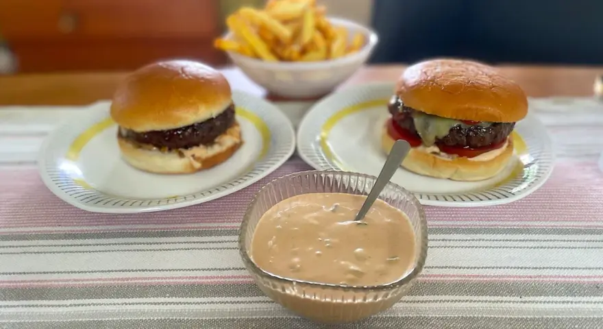 Två hamburgare med pommes frites och en skål med hemlagad hamburgerdressing. Perfekt för en mysig hemmakväll!