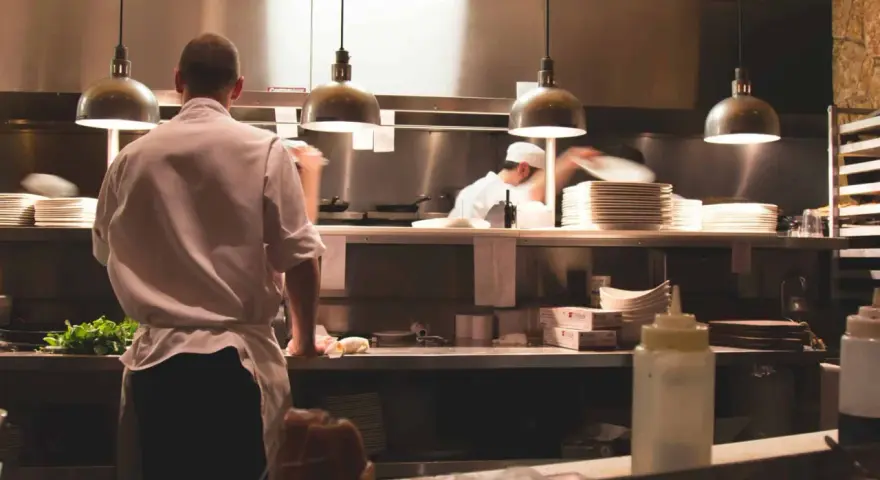 Kucharz w białej koszuli i fartuchu pracuje w kuchni restauracyjnej. To idealne miejsce, by napisać list motywacyjny kucharz.