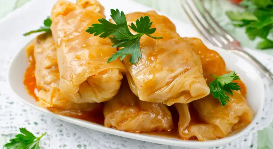 Talerz gołąbków w sosie, udekorowany natką pietruszki. Zastanawiasz się, ile kcal ma gołąbek?
