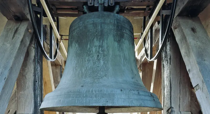 Große, grüne Kirchenglocke im Glockenturm, bereit zum Läuten an Ostern.
