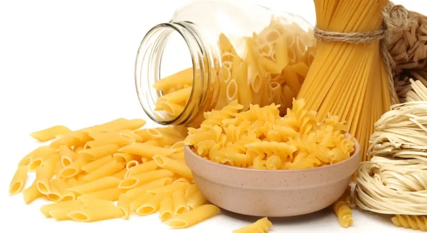 Różne rodzaje makaronu: penne, fusilli w miseczce, spaghetti nr 5 i spaghettini.