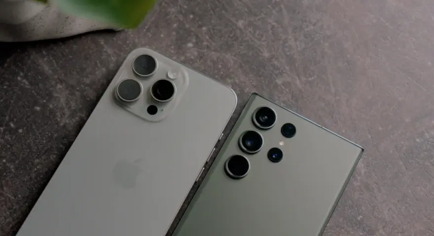 Dwa najnowsze fotosmartfony, iPhone i Samsung, leżą obok siebie na ciemnym tle.
